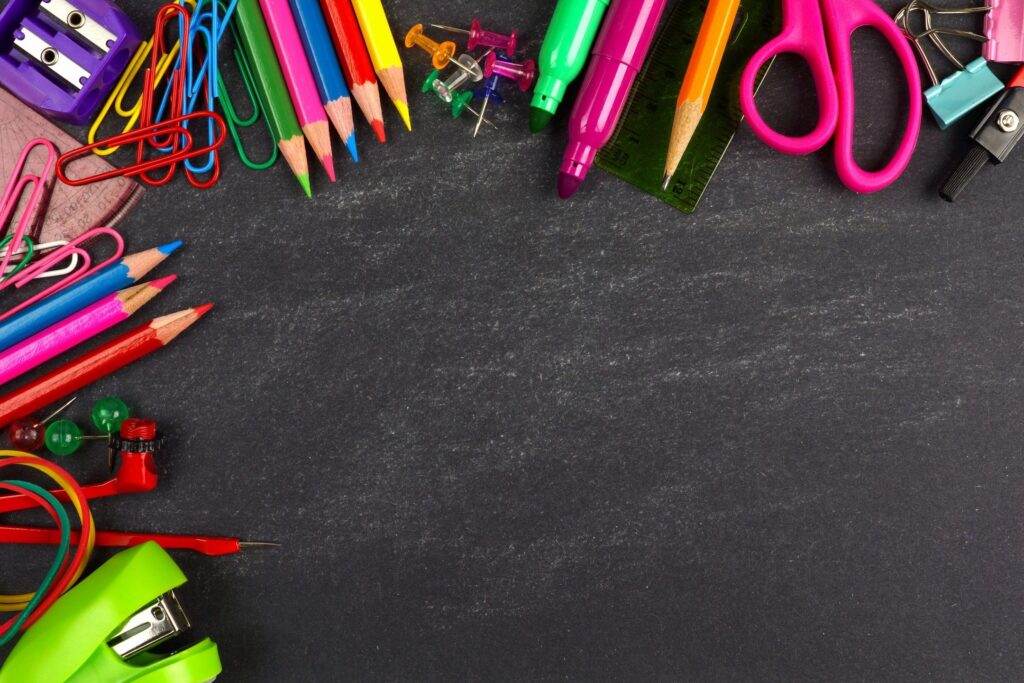 A chalkboard with lots of different colored pencils and pens.