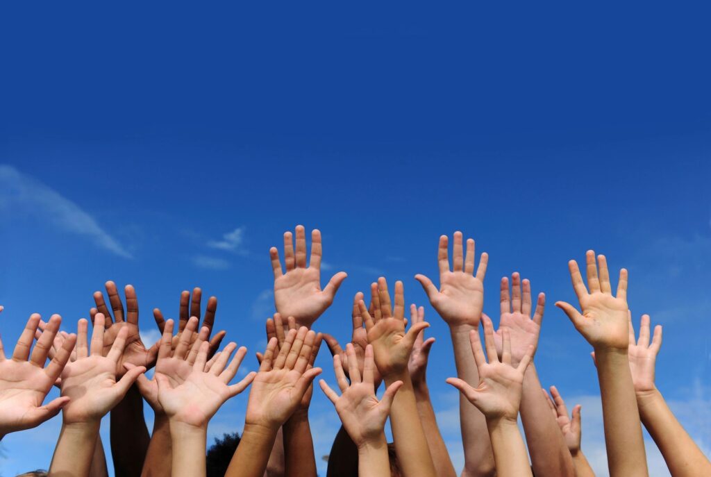 A group of people raising their hands in the air.