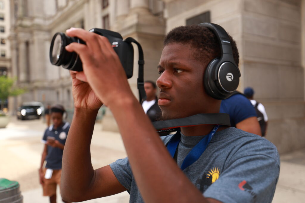 A man with headphones on holding up a camera.